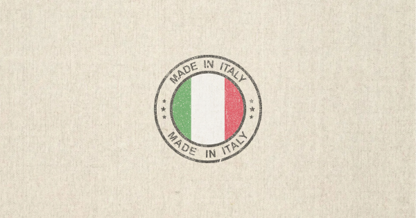 Schriftzug ‘MADE IN ITALY’ in schwarzer Großbuchstaben-Typografie auf beigem Hintergrund, darüber ein horizontaler Streifen in den Farben der italienischen Flagge – grün, weiß und rot